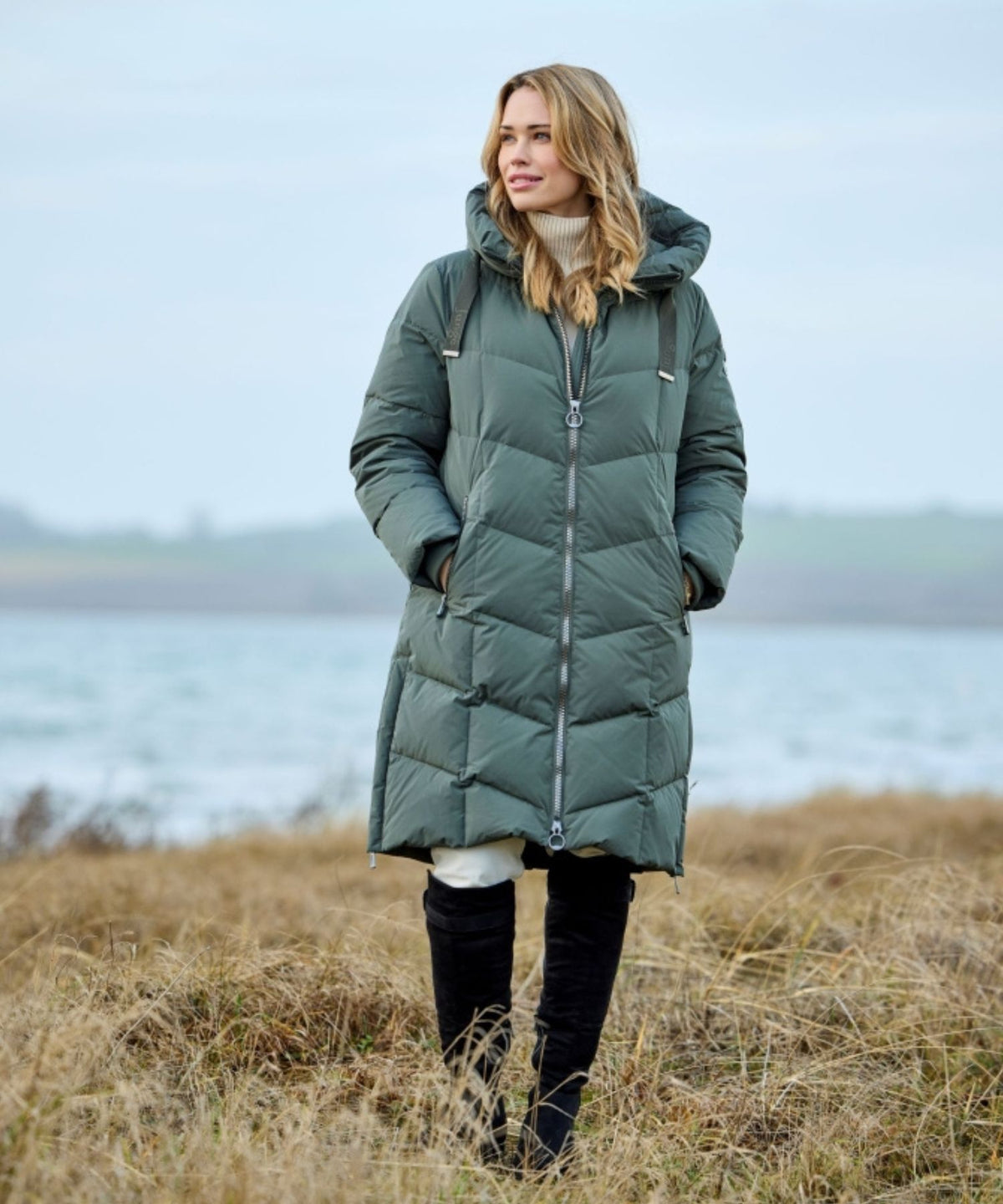 Junge Padma i olive lang dunjakke med chevronquilting i dansk kystlandskab