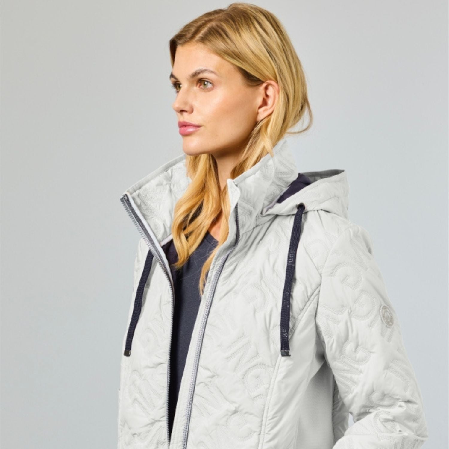 Quilted summer jacket for women in ecru with graphic JNG letter pattern and navy contrast details on zip and hood cord.
